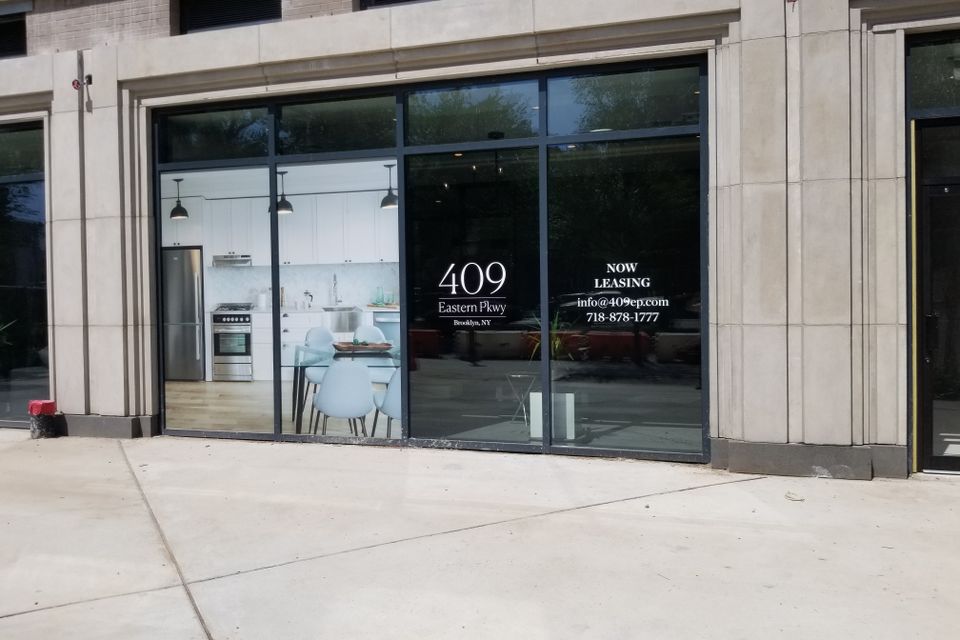 White cut-vinyl address logo and leasing details applied to a large storefront window