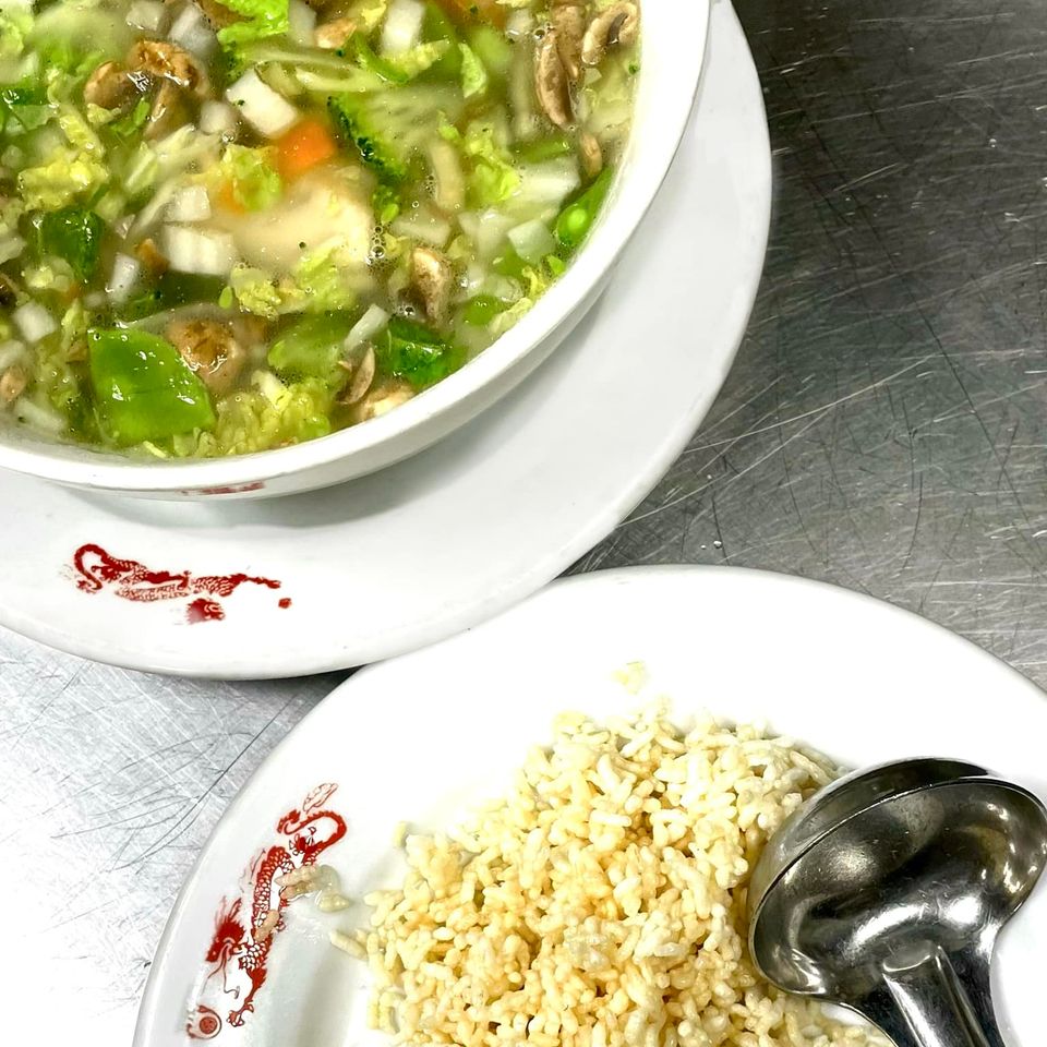 Fresh vegetable-filled soup served with crispy noodles and a soup ladle on the side.