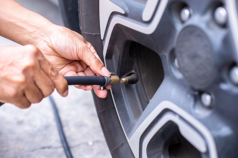Driver checking air pressure and filling air in the tires close up