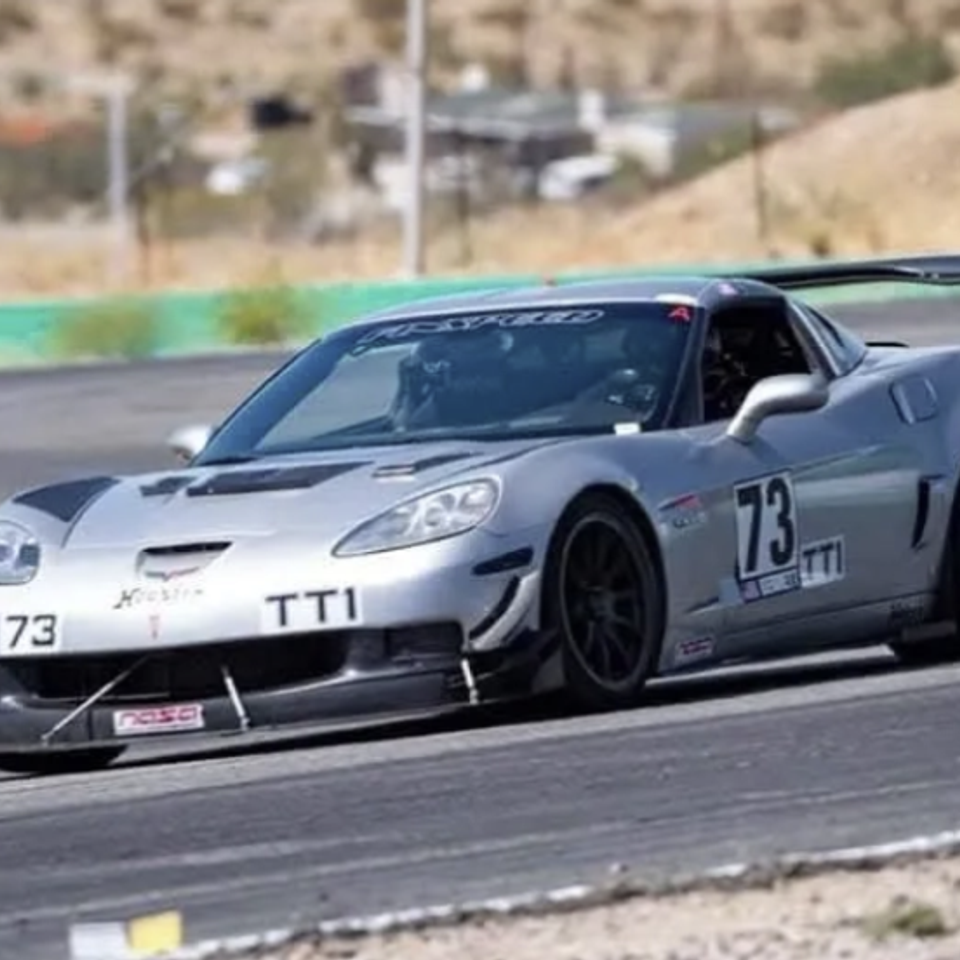 Licensed competition driver performing a comprehensive nut-and-bolt technical inspection on a race car.