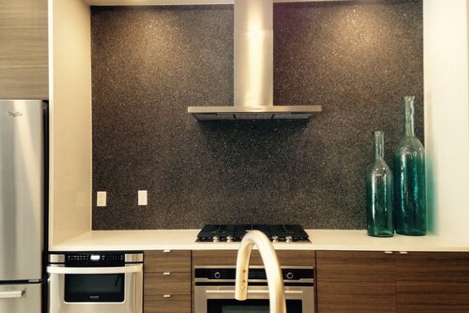 Modern kitchen with Quartz Carpet installed as a textured backsplash behind the stove.