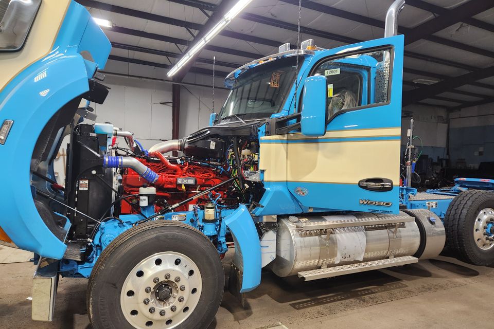 Heavy-duty semi truck inside an auto glass shop for commercial windshield replacement and glass service.
