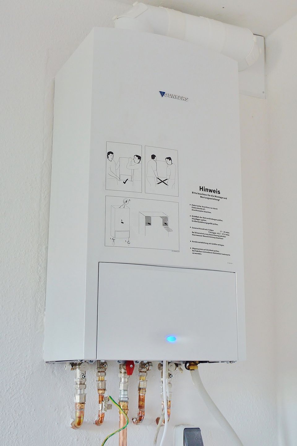 White propane tankless water heater installed in a home utility room