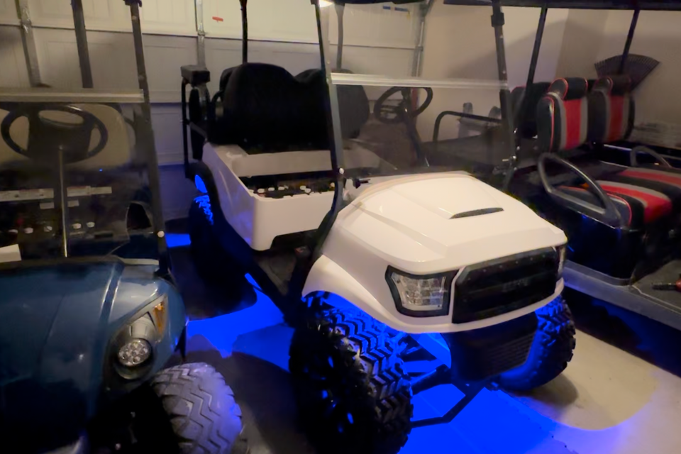 White custom golf cart with blue undercarriage lights parked in a garage in New Orleans, LA