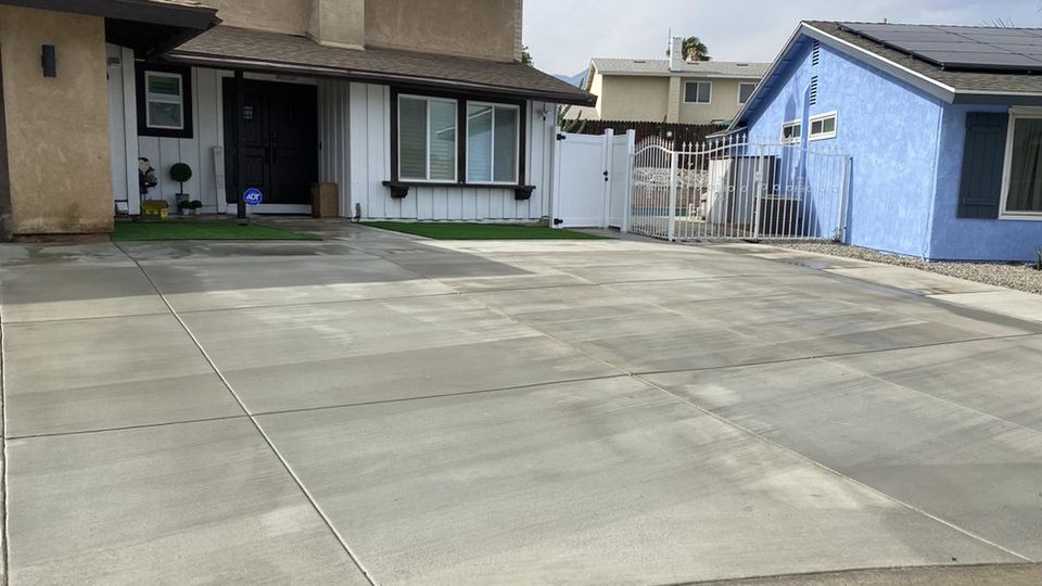 Newly installed large concrete driveway in front of residential home with smooth finish and clean expansion joints