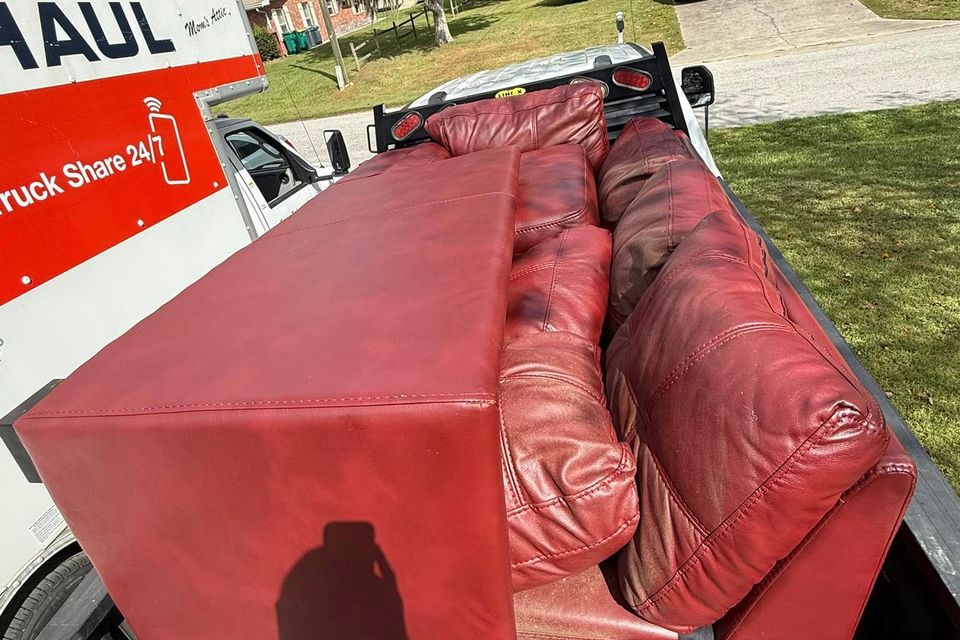 A red couch being transported by JNJ Hauling Solutions of Citrus County
