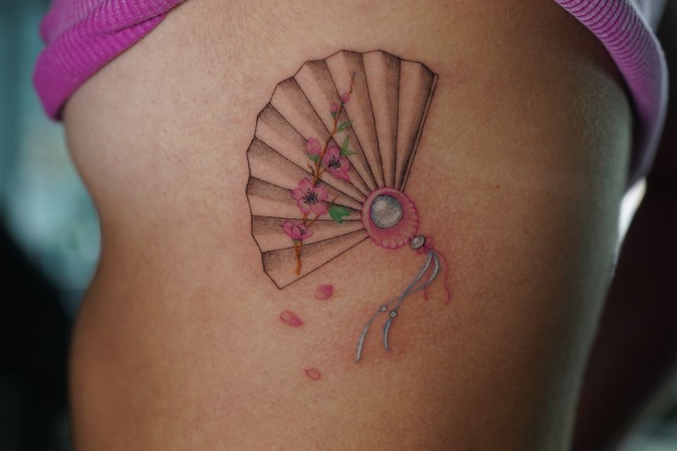 Image of a Collapsable fan tattood on the upper torso of a woman