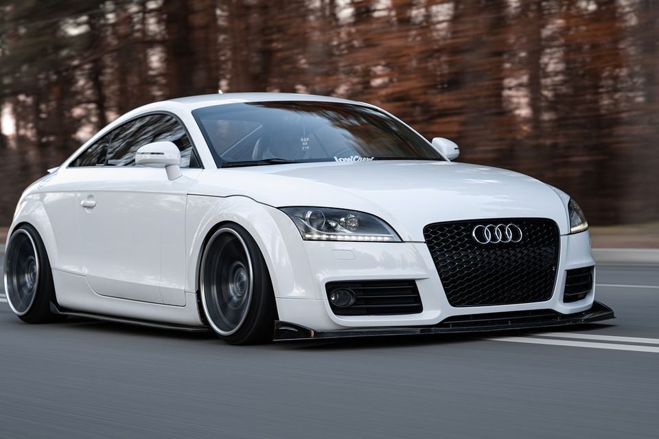 Image of audi coupe, white from passenger front quarter panel view, moving down the road, straight ahead