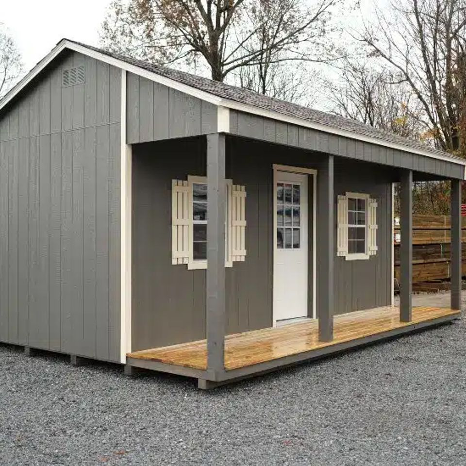Gray country cabin with covered porch, shutters and white entry door in Knoxville TN