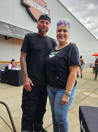 Kelly standing with another event attendee outside a motorcycle venue during a community event.