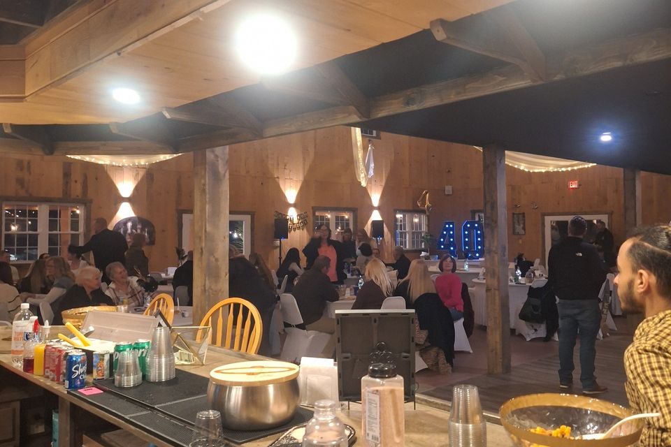 Indoor event with guests seated and a bar setup in a rustic venue