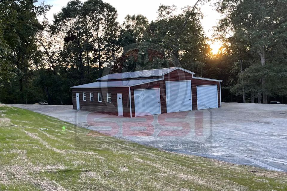 Red and white steel garage with multiple roll up doors at sunset with SBSI watermark representing steel garages in Alabama