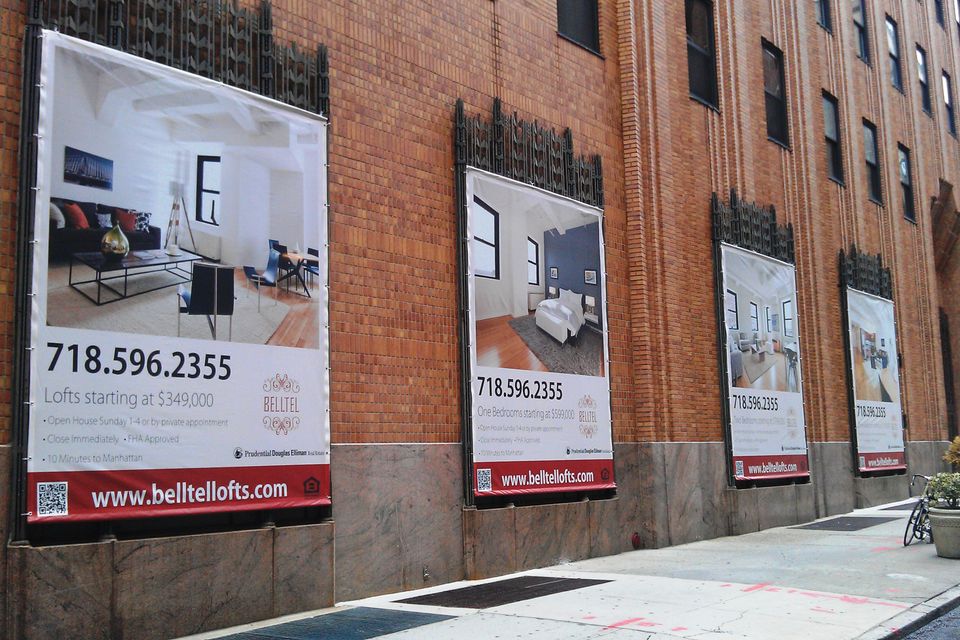 Row of printed vinyl banners advertising Belltel Lofts on a brick building facade in Brooklyn