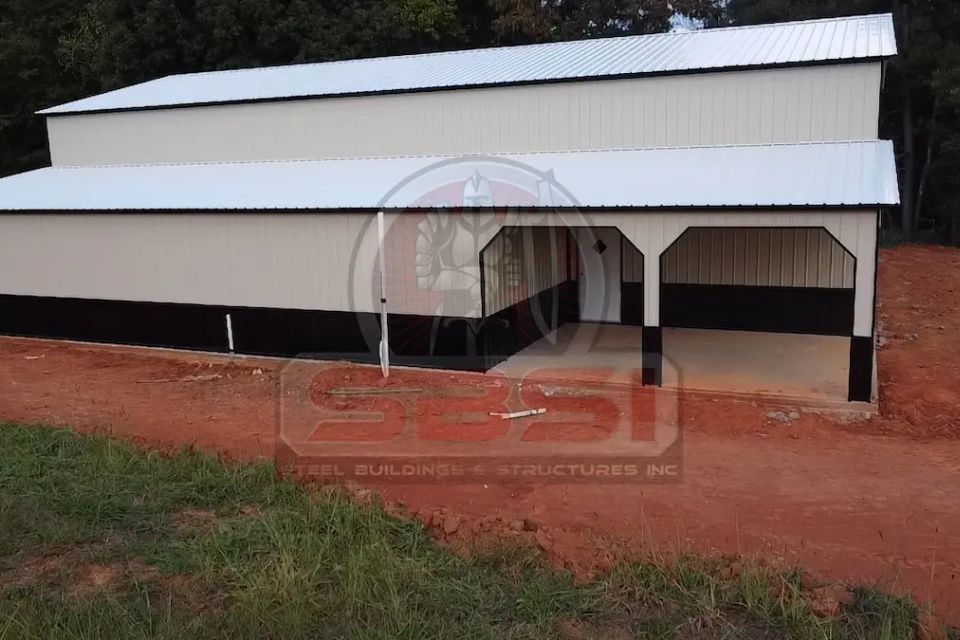 Tan and black steel barn with open center bays and red trim with SBSI watermark representing steel barns in Alabama