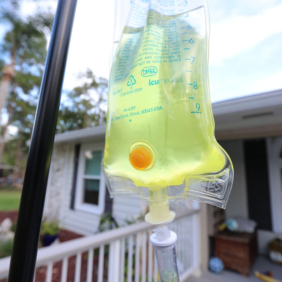 Yellow vitamin IV bag hanging on a pole outside a home during a mobile IV drip visit in Palm Beach County FL