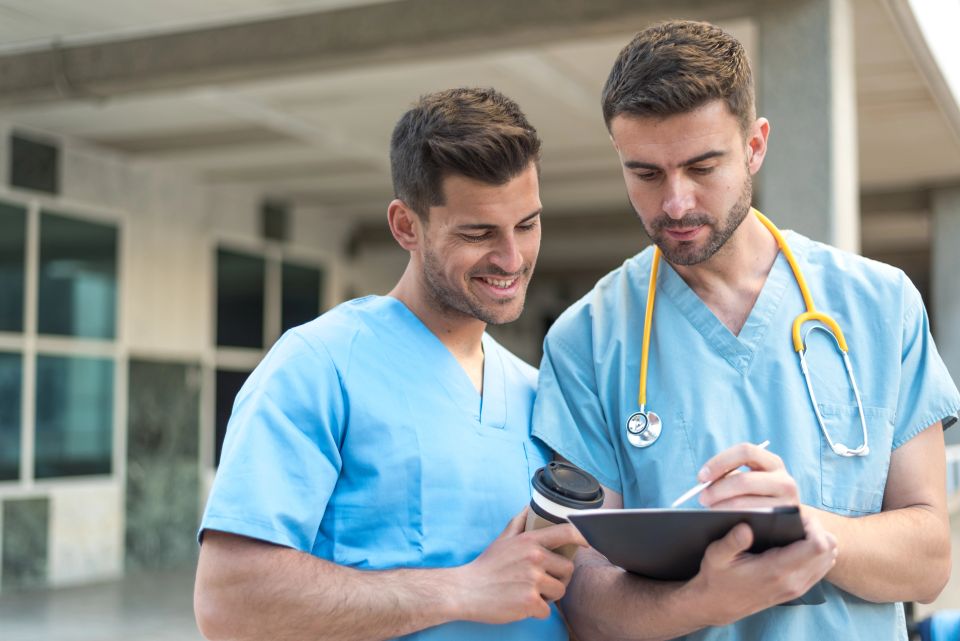 Two male licensed nurses reviewing a clipboard, representing professional and diligent patient care.