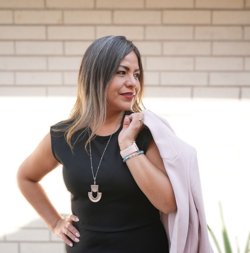Nancy delgado owner of nadel design in black outfit  with light colored jacket strewn over shoulder