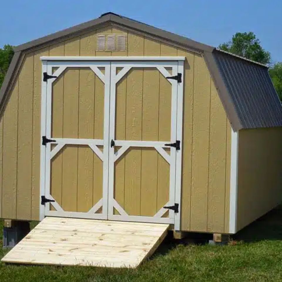 Tan mini barn shed with white trim doors and wood ramp installed in East Tennessee