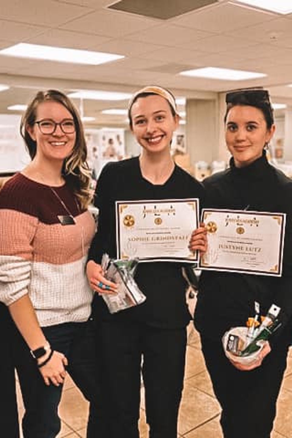 Group of beauty school graduates holding certificates together