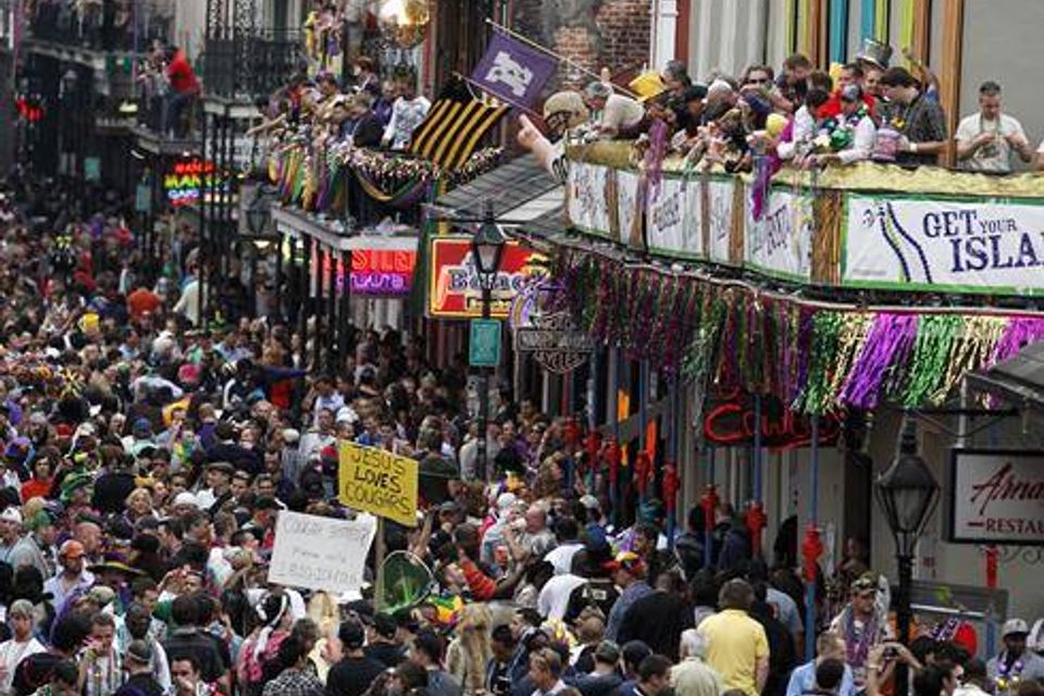 Balcony on Bourbon Street with party goers looking down at the wall to wall crowds on Bourbon Street in New Orleans.