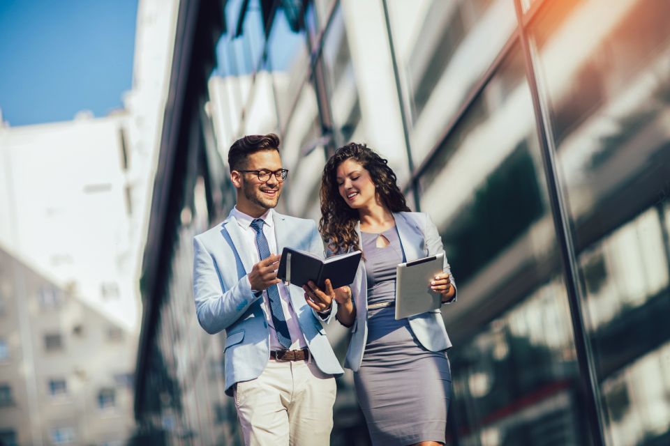 A man and woman outside looking on their digital tablet