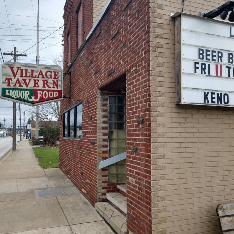 Exterior of Village Tavern with sidewalk sign and event board outside the building