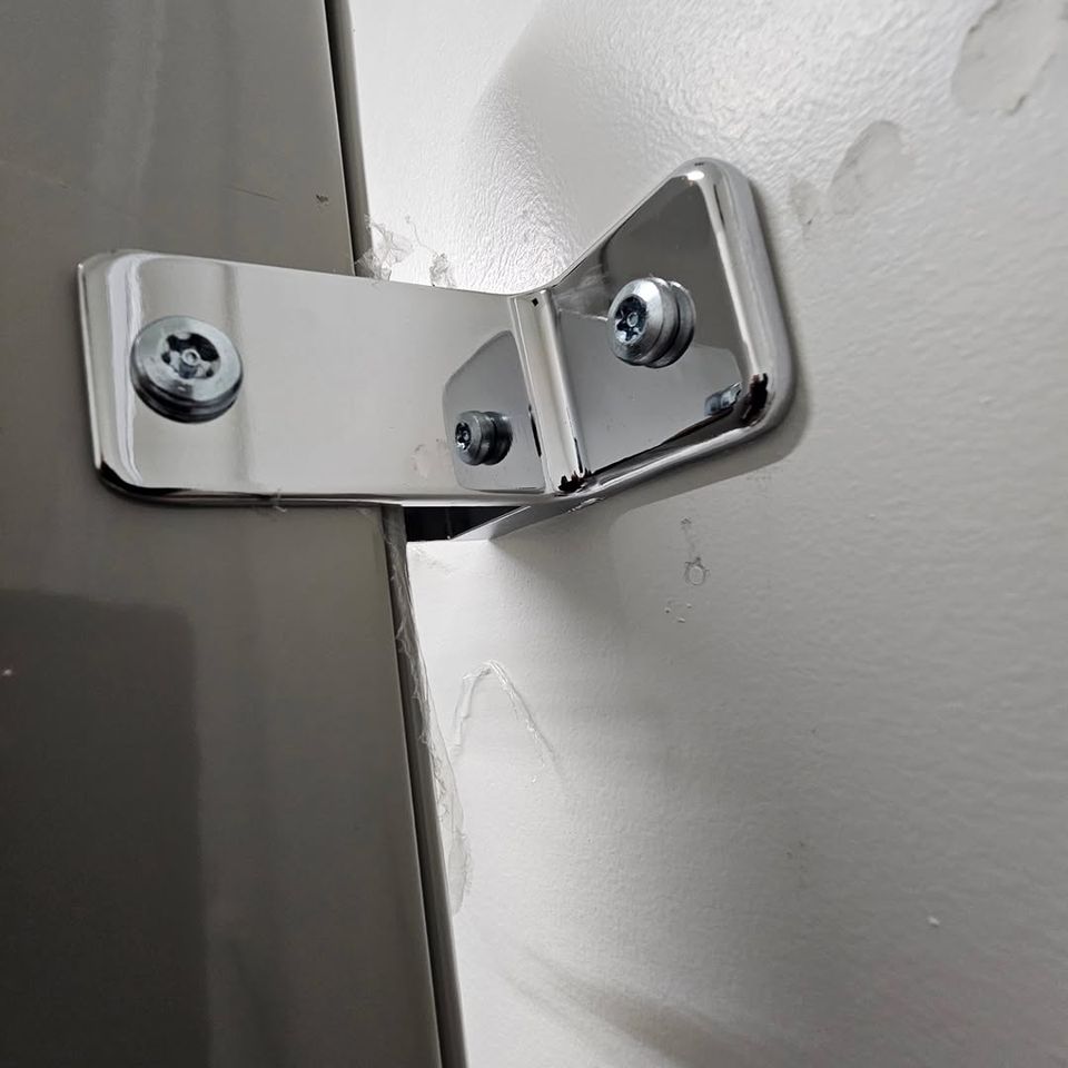 A bathroom partition screwed into a wall done by Pabst Leyton in Southern California