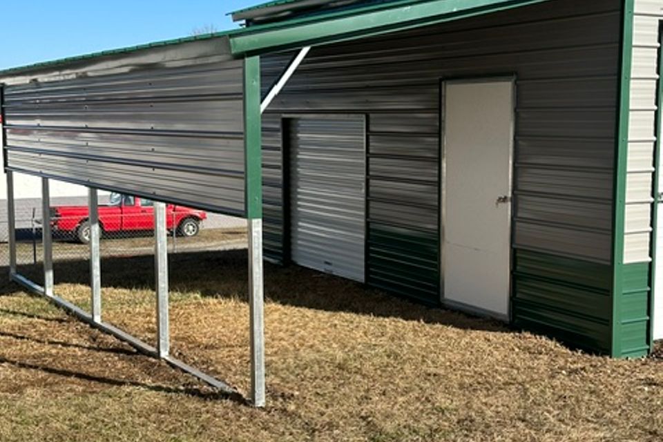 Green steel building with side lean to and white entry door representing steel buildings in Alabama