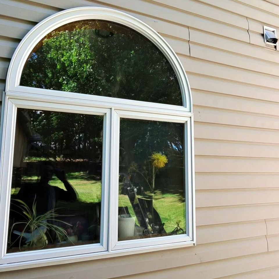 Clean arched white-trimmed window on tan vinyl siding after window washing in Harrisburg PA