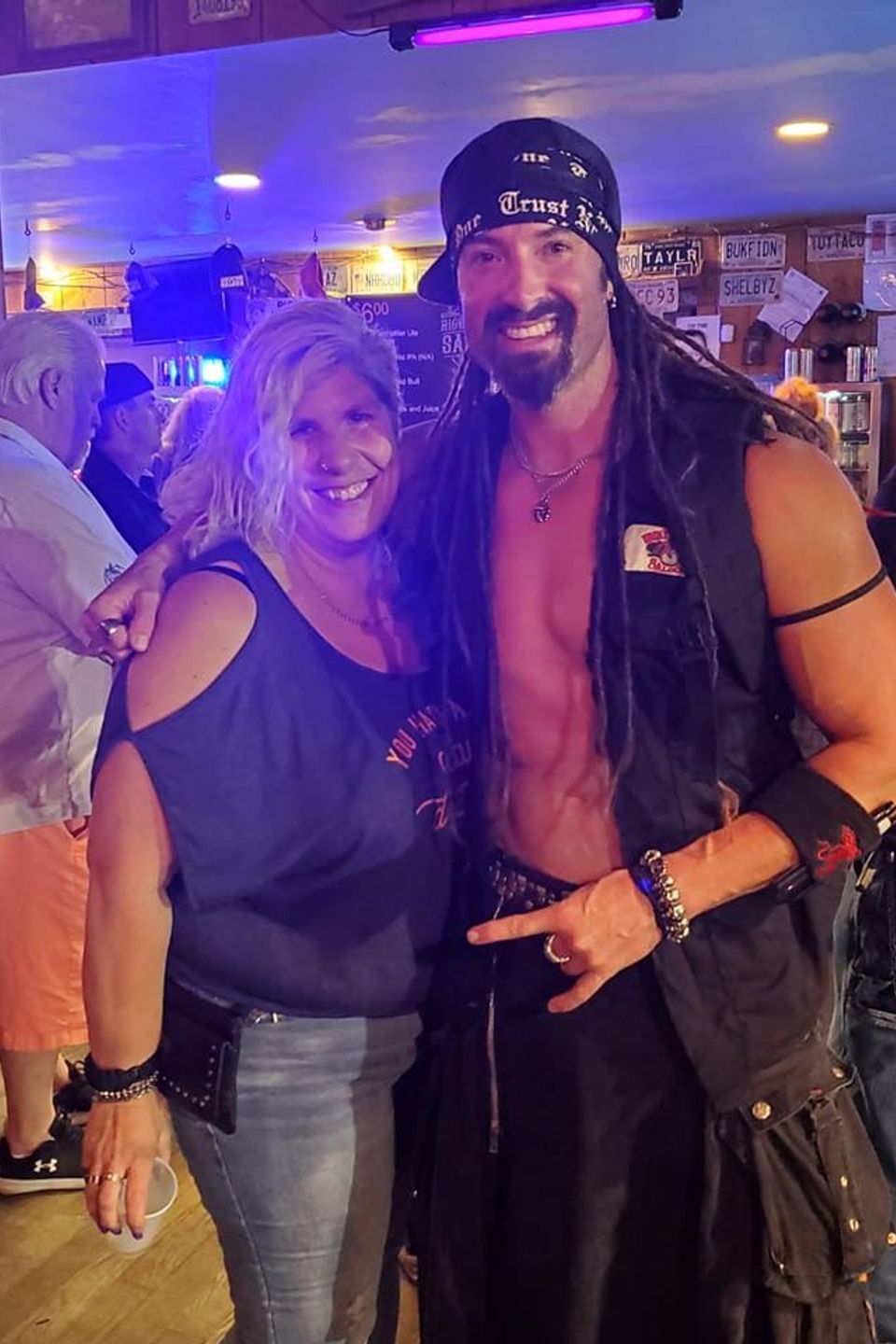 Woman posing with a costumed guest at a social event.