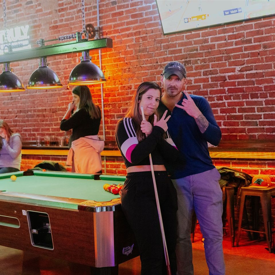 Lady and gentleman posing in front of pool table