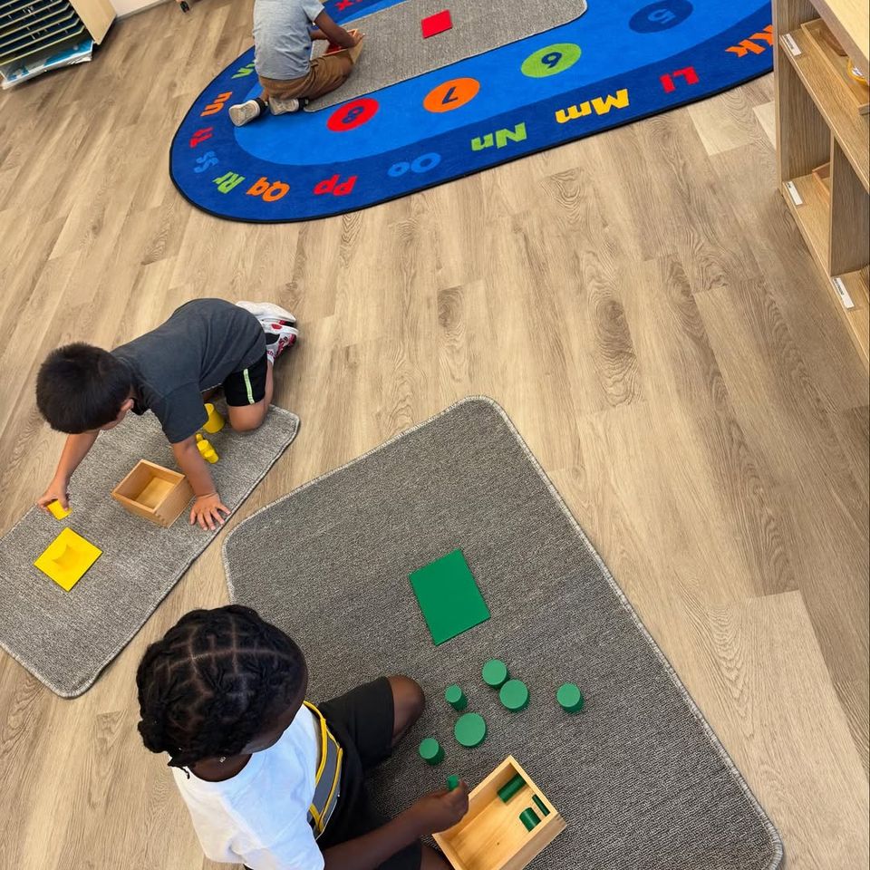 Preschool boys working with Montessori sensorial materials on floor mats in a bright classroom in Palmdale CA