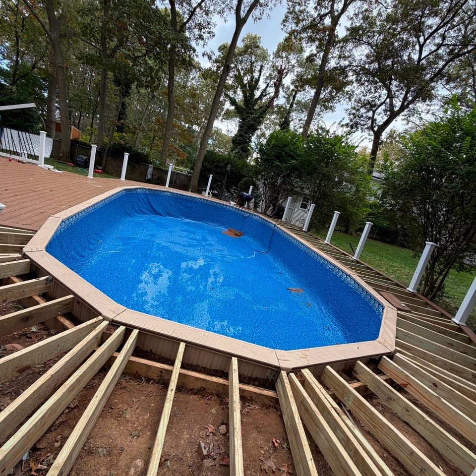 Oval above ground pool with new liner surrounded by a wood deck under construction