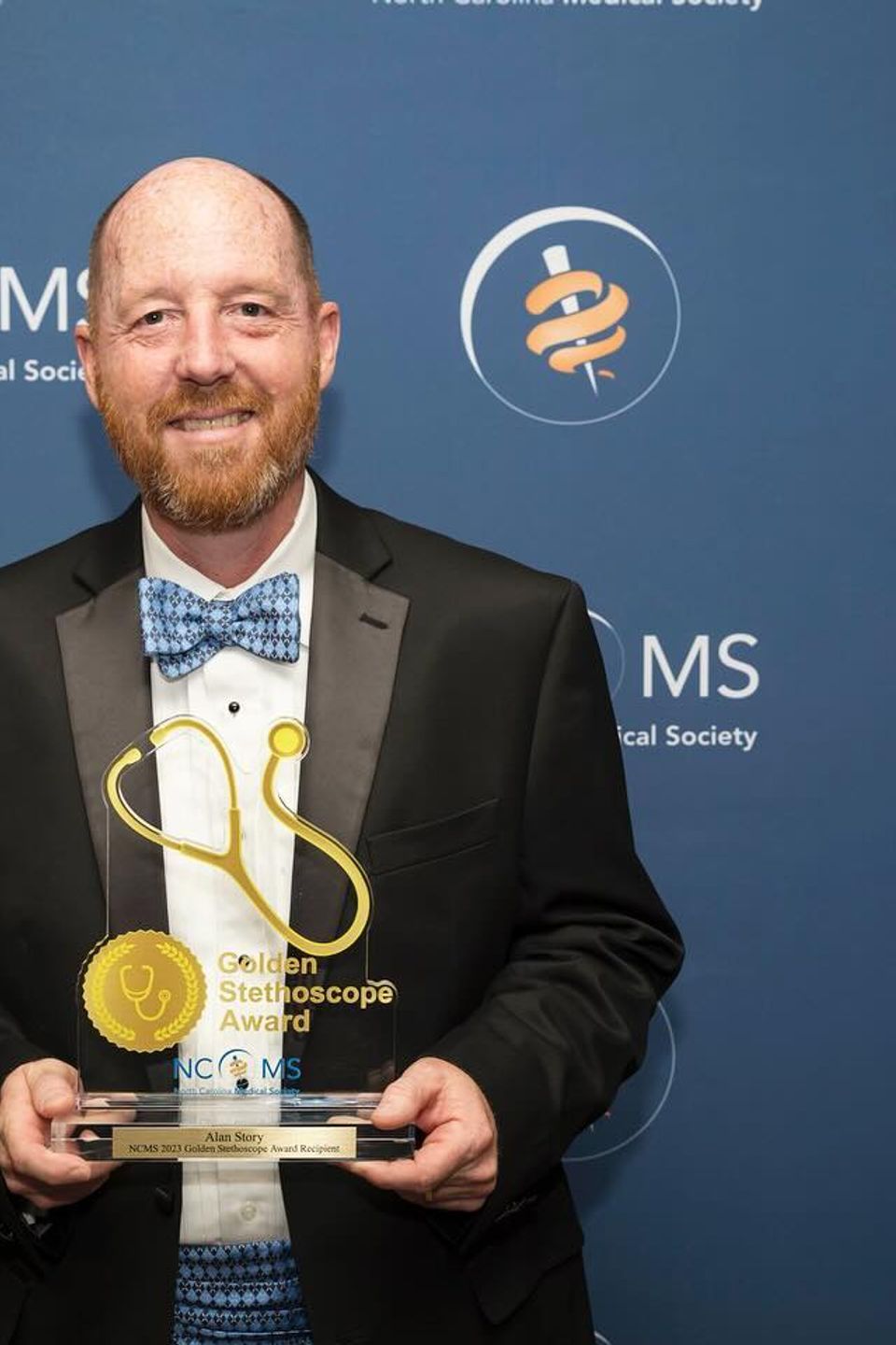 Dr Story Holding the Golden Stethoscope Award