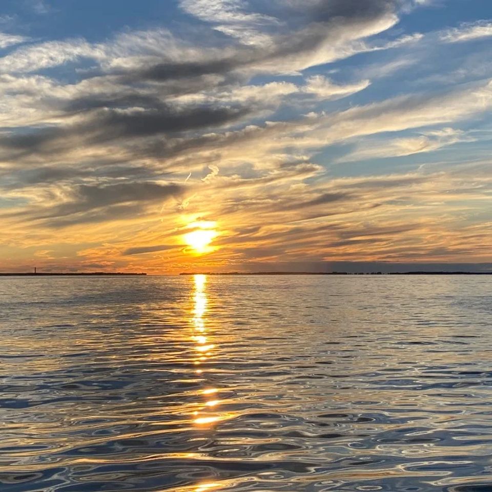 Vibrant Charleston Harbor sunset reflecting on calm ocean waters with dramatic clouds