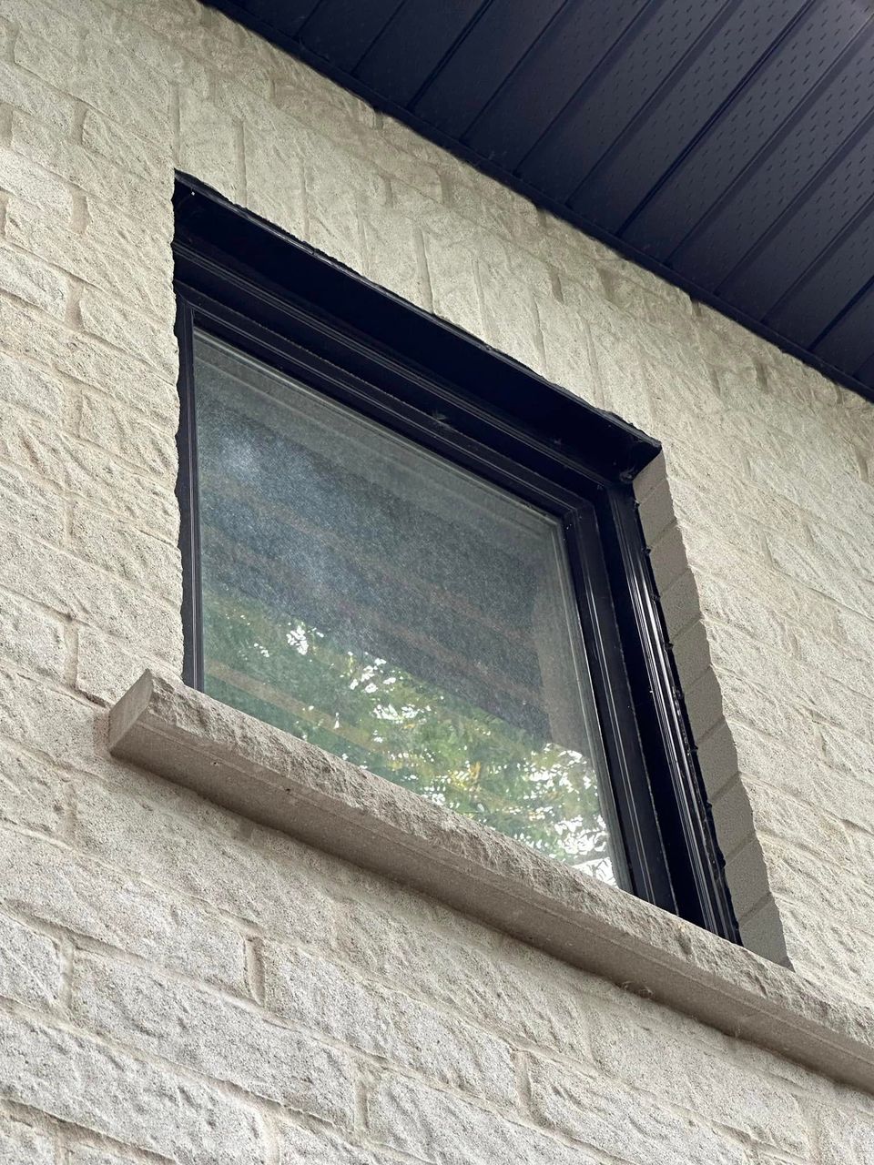 Hazy dirt-covered window on a stone exterior before a professional window washing