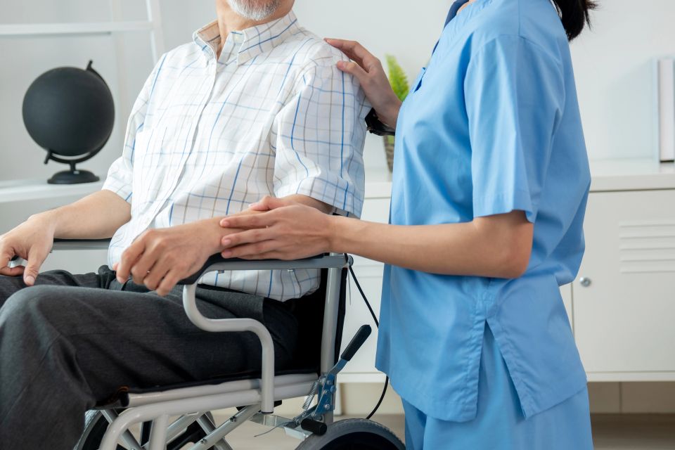 A female nurse caring for her patient who is in a wheelchair