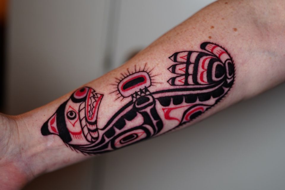 Image of a Mayan or Aztec dog lying down in red and black colored ink