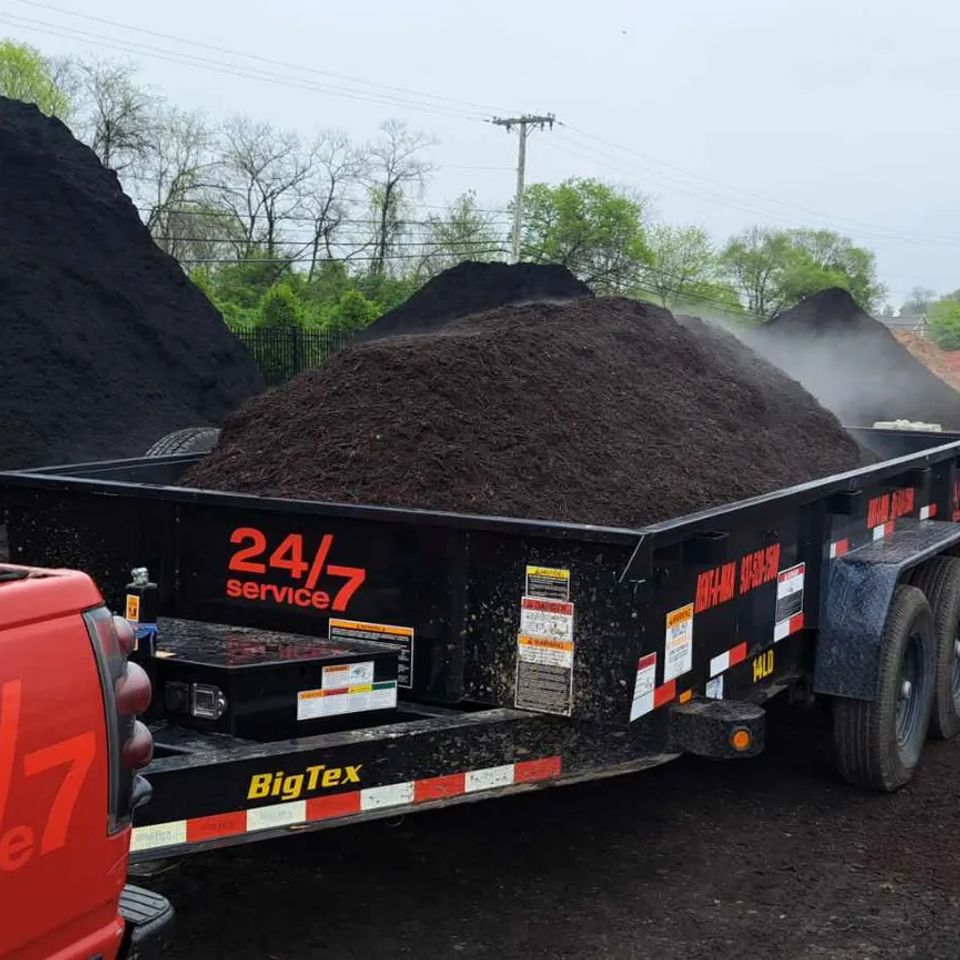 Trailer loaded with dark mulch at a landscape supply yard ready for delivery.
