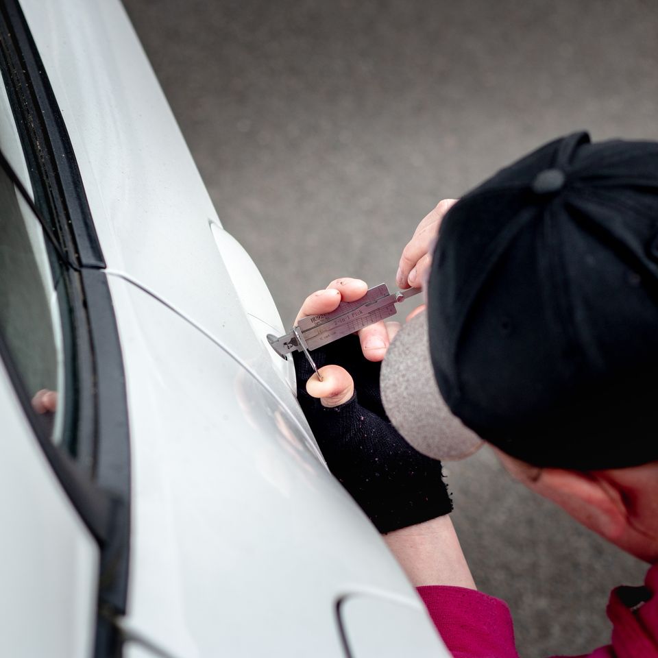 Car locksmith using professional tools to unlock a car door
