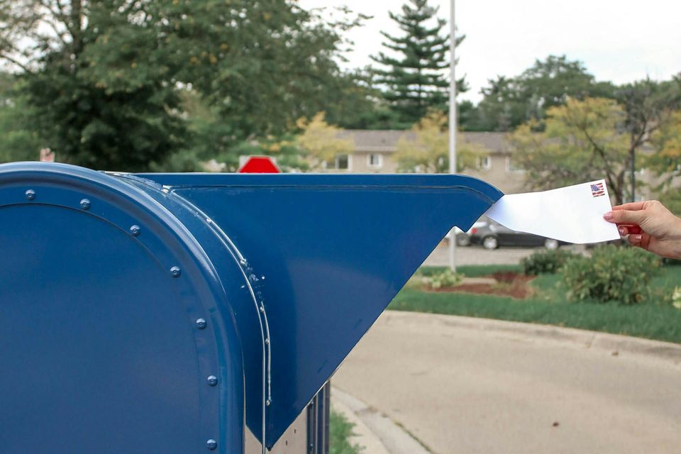 Person putting mail in the postal mailbox