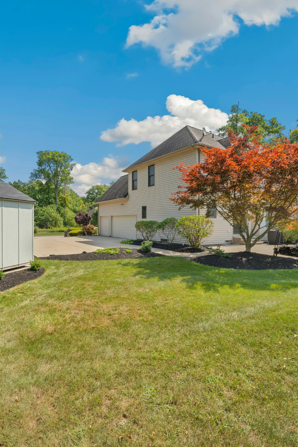 Well-maintained residential property with a manicured lawn, fresh mulch beds, ornamental trees, and neatly trimmed shrubs maintained by R.E.P. Companies.
