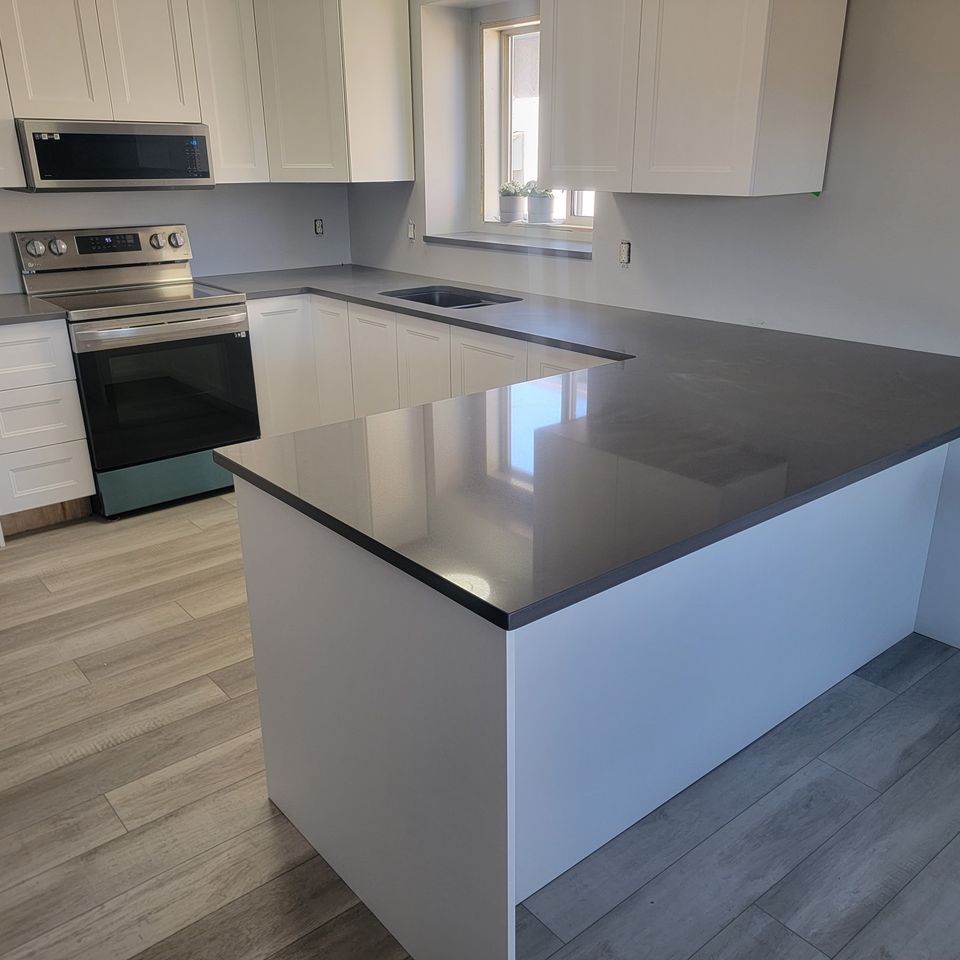 Black countertop with white cupboards and laminate flooring