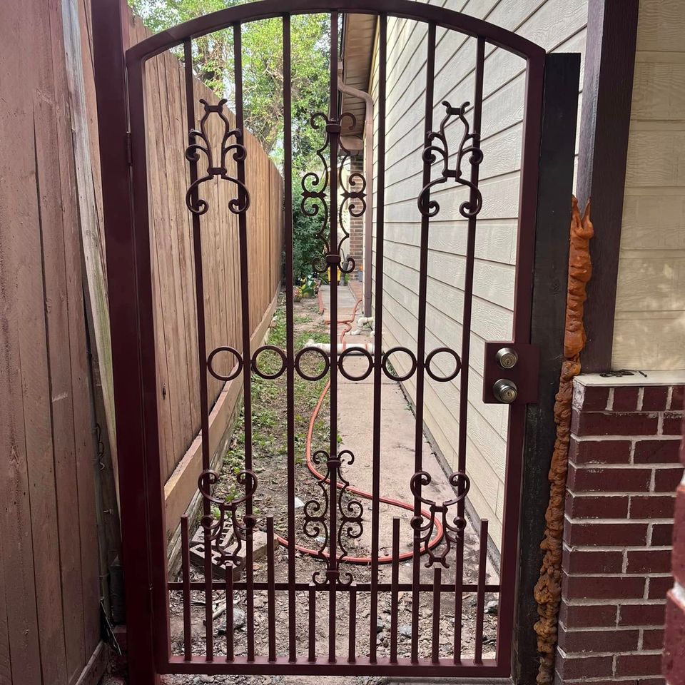 Black iron walk-through gate with decorative welded design built by Marquez Welding in Houston