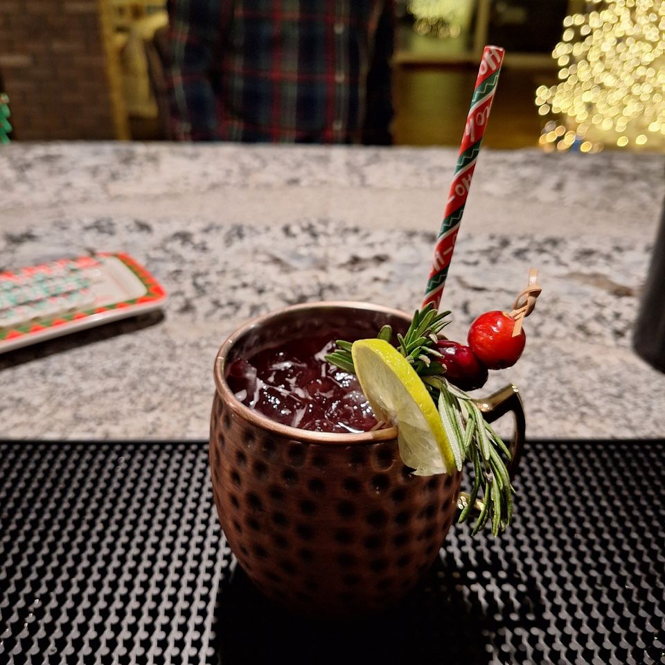 Berry and Bright Mule with lime, rosemary, and cranberry garnish on a bar counter