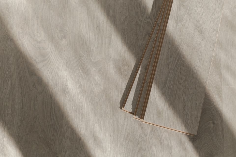 Light oak laminate planks laid on a finished floor with sunlight across the surface