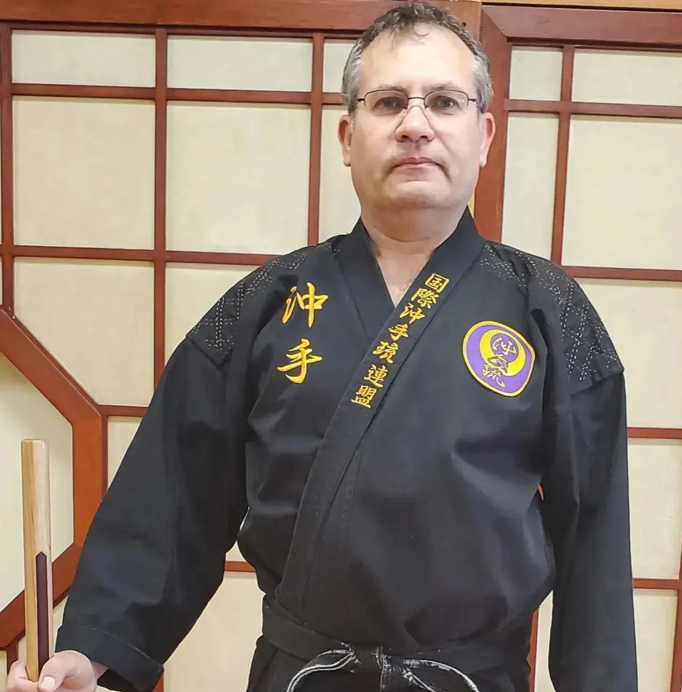 Kyoshi Manny Soares posing with karate weapons at Takamine Karate Dojo in Miller Place