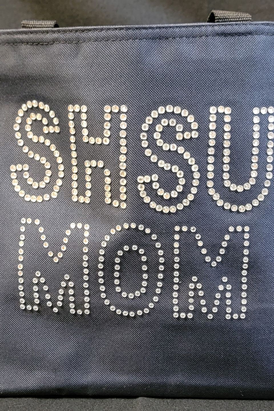 This is an example of a navy tote bag decorated with rhinestone bling that reads "SHSU MOM".