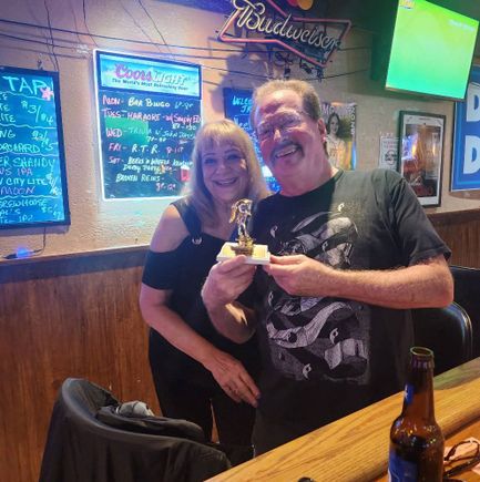 Two guests at JR's Kentucky Derby 2025 event posing with a trophy inside the bar.