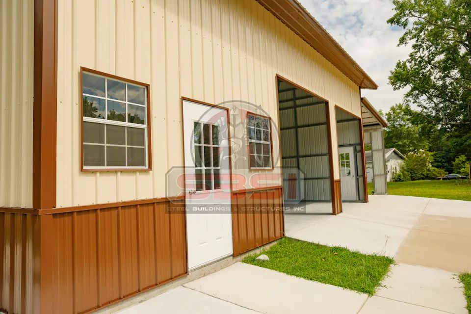 Tan steel building with brown wainscot and white entry door with SBSI watermark representing custom steel buildings in Alabama
